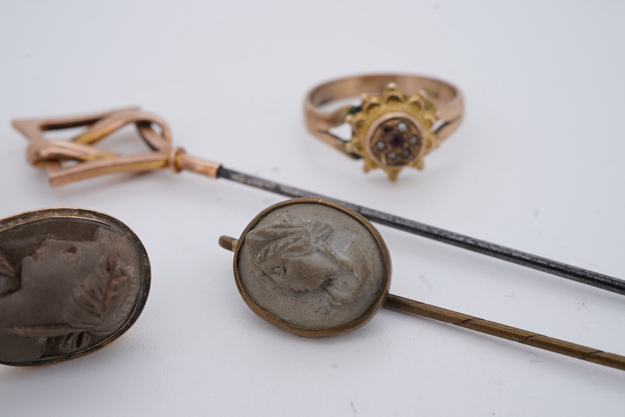 A collection of jewellery, comprising: a brooch, pair of earrings and a stick pin set with lava cameos; a stick pin capped with a geometric motif in gold, stamped 9CT; and a ring set with seed pearls and a garnet